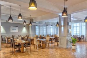 a dining room with tables and chairs and windows at Hotel Mevora in Tbilisi City