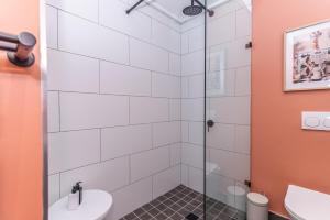 a bathroom with a shower with a toilet and a sink at Modern One Bedroom Wavescapes Apartment Muizenberg in Muizenberg +16 photos