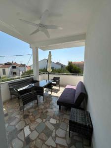 a patio with chairs and tables and a ceiling fan at Apartmány Zuzana in Primošten