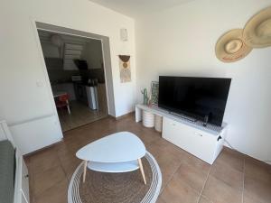 a living room with a tv and a table and a stool at Logement proche Aéroport Nantes in Saint-Aignan-Grand-Lieu