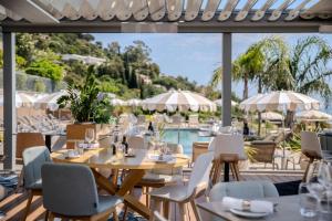 a restaurant with tables and chairs and a pool at Hôtel La Villa Douce in Rayol-Canadel-sur-Mer