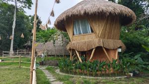 a small hut with a window in a garden at Alpaca Lodge in Tanah Lot