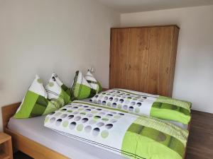 een bed met groene en witte lakens en kussens bij Haus Perle in Saas-Fee