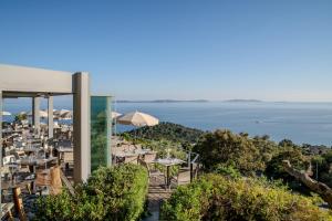 a restaurant with tables and umbrellas overlooking the ocean at Hôtel La Villa Douce in Rayol-Canadel-sur-Mer