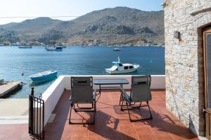 a patio with a table and two chairs and a boat at Mythos House - Seaside Retreat in Pedi in Symi