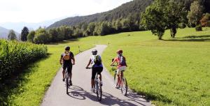 Tres personas en bicicleta por una carretera en Pitterlehof, en Chienes