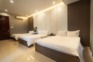 Una habitación de hotel con dos camas con sábanas blancas. en Ngoc Se Hotel, en Pleiku