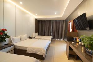a hotel room with two beds and a television at Ngoc Se Hotel in Pleiku