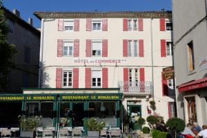 a white building with red shutters on a street at Hotel Du Commerce in Pont-Saint-Esprit