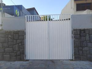 ein weißes Tor vor einer Steinmauer in der Unterkunft Casa no Bairro da Prata, para até 8 pessoas, 150mt do PP in Campina Grande