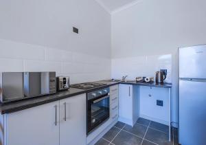 Una cocina con gabinetes blancos y electrodomésticos azules. en The Aubs Self Catering Apartment, en Brackenfell