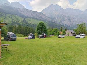 a field with tents and cars parked in front of mountains at Guest house 1 in Valbonë