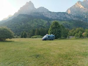 a van parked in a field with mountains in the background at Guest house 1 in Valbonë