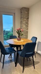 una mesa de comedor con sillas azules y un jarrón con flores en Apartment Tomy, en Rijeka