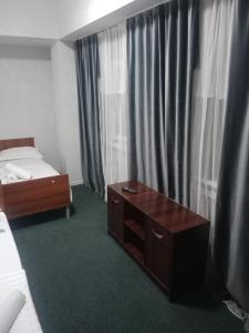 a bedroom with a bed and a dresser and a table at Айымхан in Almaty