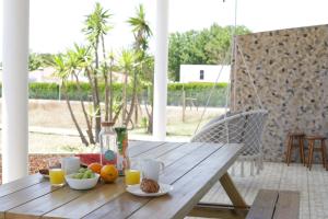 a wooden table with fruit and drinks on a porch at Casa Silva in Zambujeira do Mar