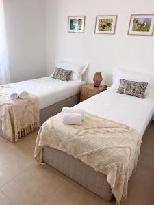 two twin beds in a white room with towels on them at Casa Silva in Zambujeira do Mar +57 photos