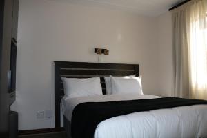 a bedroom with a large bed with white sheets and pillows at Melrose Corner Self-Catering Hotel Apartments in Johannesburg