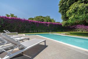 a swimming pool with chairs and a hedge with purple flowers at Il Giardino di Venere in Mondello