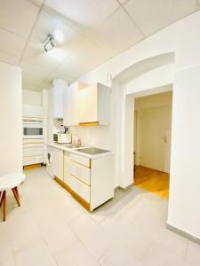 an empty kitchen with white cabinets and a table at Sweet 3-Bedroom shared Apartment in a Quiet Neighborhood in Vienna