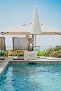 a pool with an umbrella and a chair next to a pool at Hôtel La Villa Douce in Rayol-Canadel-sur-Mer