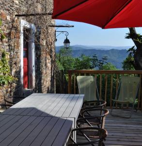 una mesa de madera con sillas y una sombrilla en una terraza en Gîte du Grand Sourel, sa vue et son jardin, en Moissac-Vallée-Française
