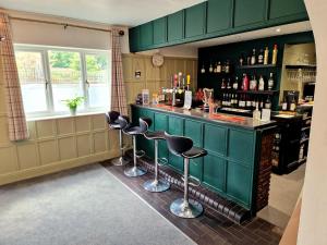 a bar with green cabinets and stools in a room at The Kensington in Great Yarmouth