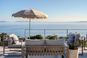 a patio with a table and chairs and an umbrella at Hôtel La Villa Douce in Rayol-Canadel-sur-Mer
