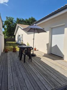 a table and an umbrella on a wooden deck at Charmant logement neuf in Hourtin