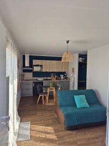 a living room with a blue couch and a kitchen at Charmant logement neuf in Hourtin