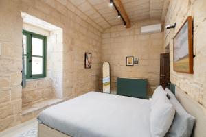 a bedroom with a white bed in a stone wall at Trinity house with a private rooftop pool in Is-Simblija +91 photos