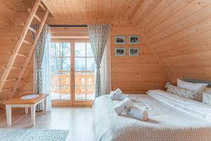 two beds in a wooden room with a window at Marusina Chalets - Luksusowy domek z jacuzzi z widokiem na Tatry in Szaflary