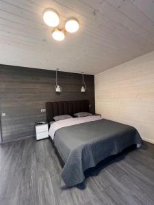 a bedroom with a large bed and a wooden wall at pro100 house in Volosyanka