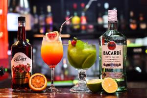 two bottles of alcohol and two cocktails on a bar at Apto aire acondicionado 100 m de la playa bicicletas gratis in Puerto Viejo