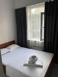 a pair of towels on a bed with a window at Айымхан in Almaty
