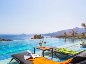 a pool with two chairs and a table with wine glasses at Eco Villa Panaroma in Kalkan
