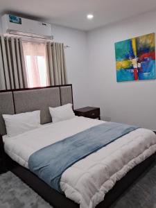 a bedroom with a large bed with a painting on the wall at Dunslim Apartments in Lusaka