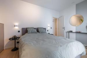a white bedroom with a large bed with pillows at Beau Soleil in Ostend