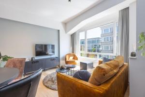 a living room with a couch and chairs and a tv at Beau Soleil in Ostend