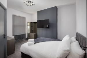 une chambre avec un grand lit blanc et une télévision dans l'établissement The Coaster Loft Apartments by STAMP SA, à Blackpool