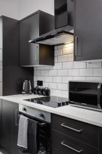 une cuisine avec des armoires noires et un micro-ondes noir dans l'établissement The Coaster Loft Apartments by STAMP SA, à Blackpool