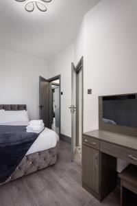 une chambre avec un lit et un bureau avec une télévision dans l'établissement The Coaster Loft Apartments by STAMP SA, à Blackpool 11 autres photos