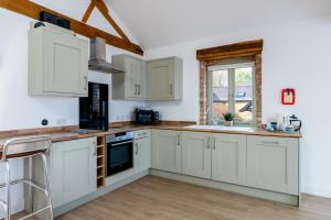 eine Küche mit weißen Schränken und einem Fenster in der Unterkunft Foxes Den at Tove Valley Cottages in Towcester