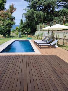 a swimming pool with chairs and an umbrella on a wooden deck at Exclusive Villa Perla & swimming pool in Bovezzo