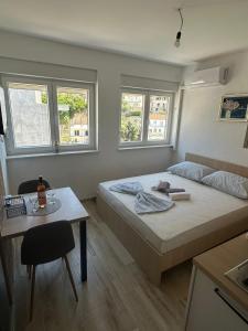 a bedroom with a bed and a table and two windows at Apartments D&M in Neum +80 photos