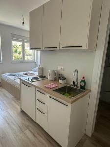 a kitchen with white cabinets and a sink and a bed at Apartments D&M in Neum