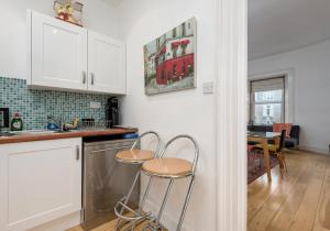 a kitchen with white cabinets and two stools at The Lothian Road Residence in Edinburgh