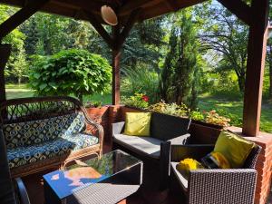 a porch with wicker chairs and a glass table at Agroturystyka Sielanka nad Stawem in Turawa