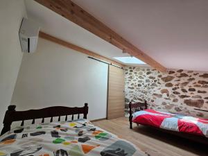 Saint-Jean-de-BuègesにあるLes mûriers de Roseのベッドと石の壁のある寝室