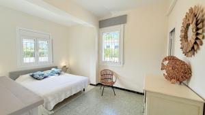a bedroom with a bed and a chair and two windows at Villa Orense 5 in Palau-Saverdera +22 photos